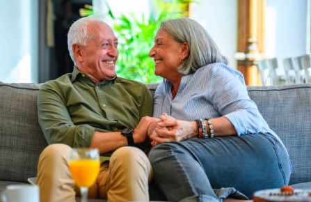 Senior man and woman seated on a sofa and smiling at each other