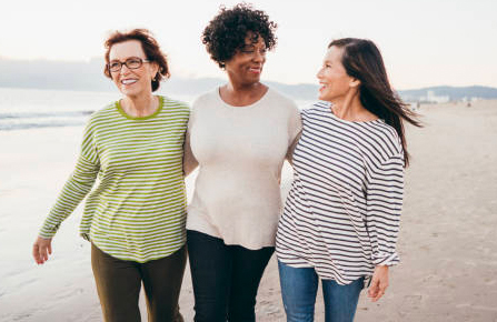 Three senior women walking along the beach arm in arm