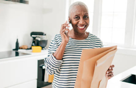 Smiling senior woman holding envelopes and listening on the phone