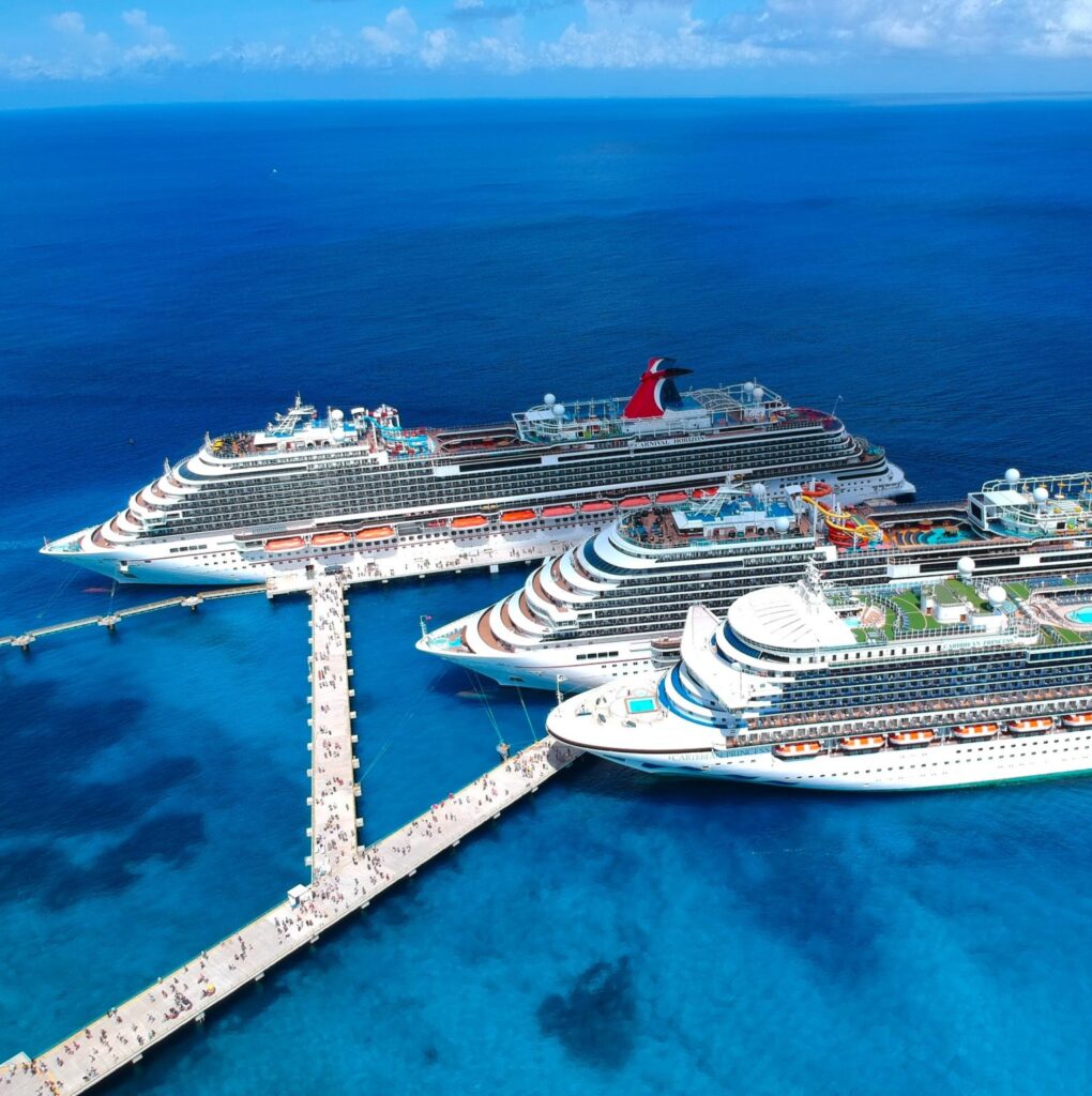 Three cruise ships with people boarding in Cozumel Mexico