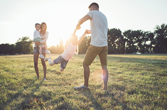 Young family playing at a park - mother, father, and two children