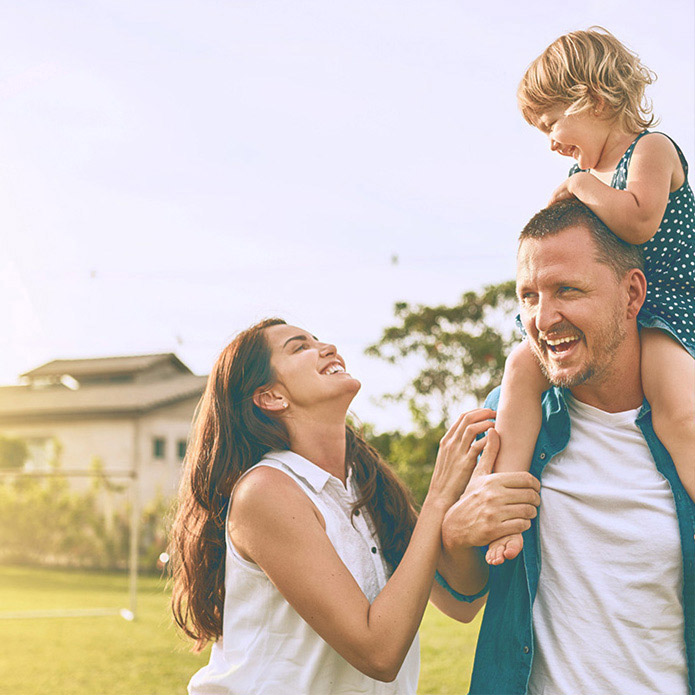 Smiling young family - mother, father, and 2-3 year old girl on dad's shoulders